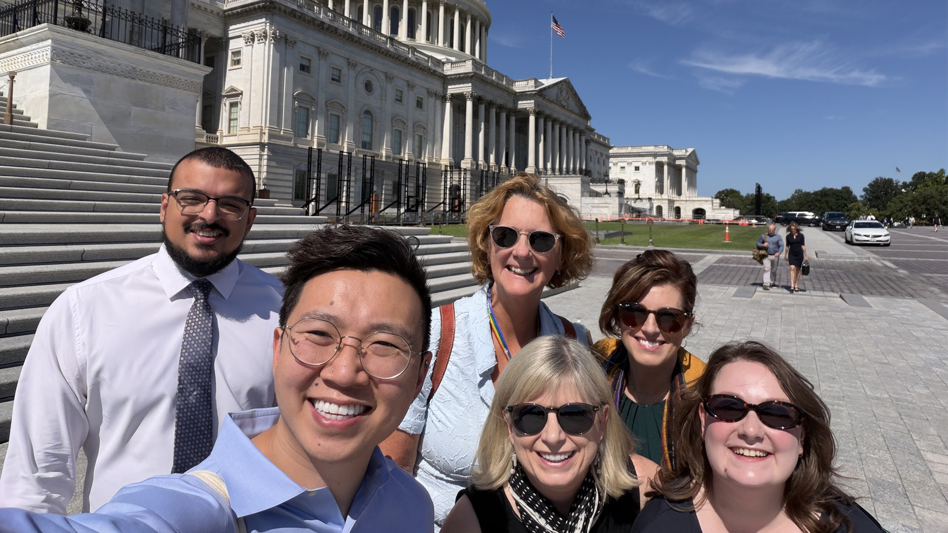 Six people pose for a photo outside the US Capitol Building.